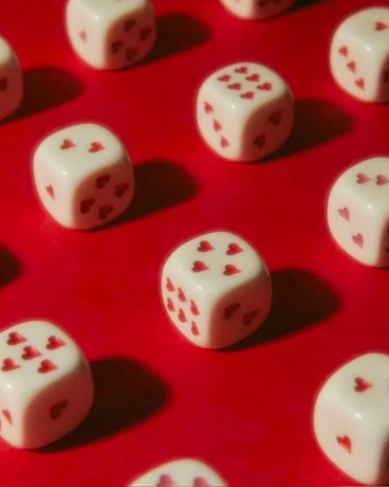 Weisse Spielwürfel mit roten Herzen auf rotem Untergrund